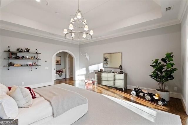 bedroom featuring ornamental molding, a chandelier, dark hardwood / wood-style flooring, and a tray ceiling