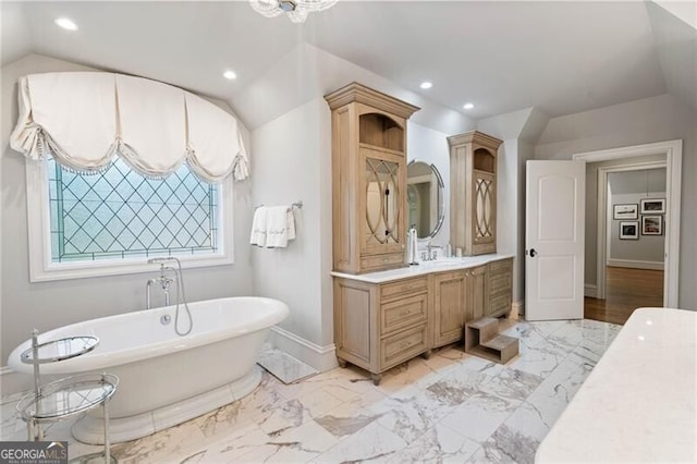 bathroom with a bathing tub, vaulted ceiling, and vanity