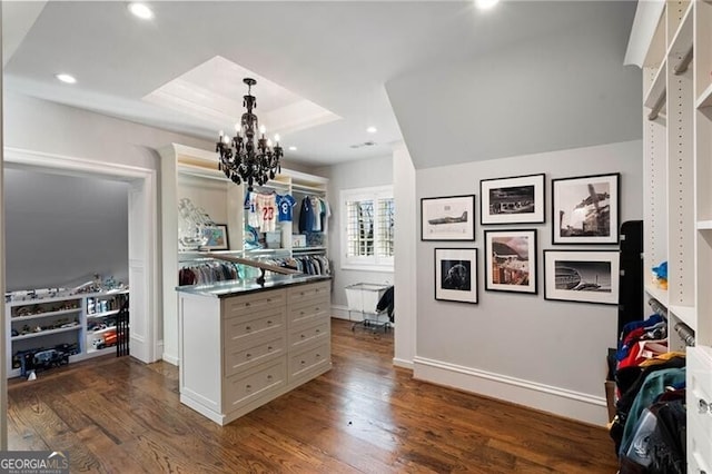 kitchen with hanging light fixtures, dark wood-type flooring, an inviting chandelier, and a tray ceiling