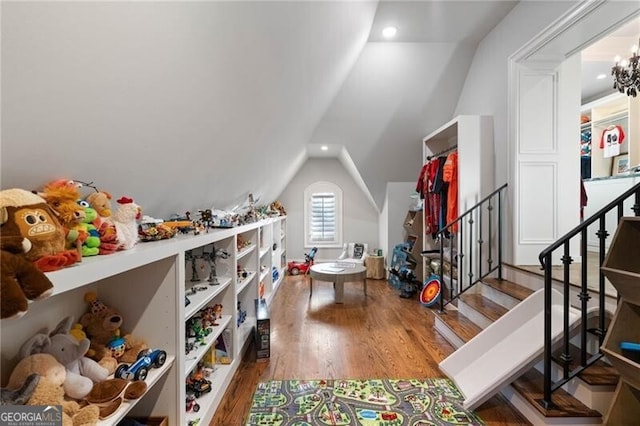 game room with hardwood / wood-style flooring, lofted ceiling, and a notable chandelier