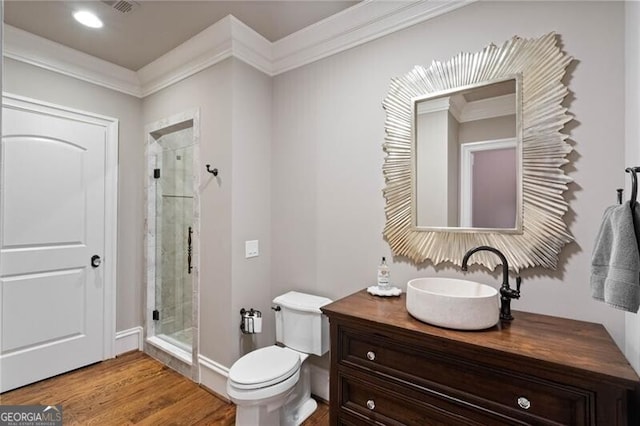 bathroom featuring wood-type flooring, toilet, a shower with door, and vanity