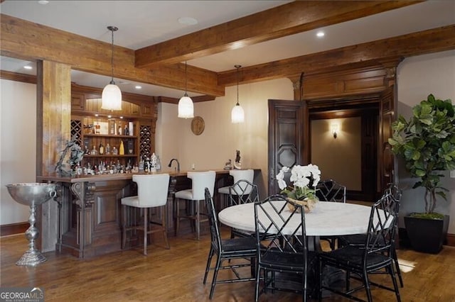 dining area with dark hardwood / wood-style floors, beam ceiling, and indoor wet bar