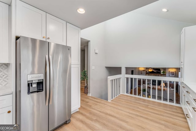 kitchen featuring stainless steel fridge, white cabinets, and light wood-type flooring