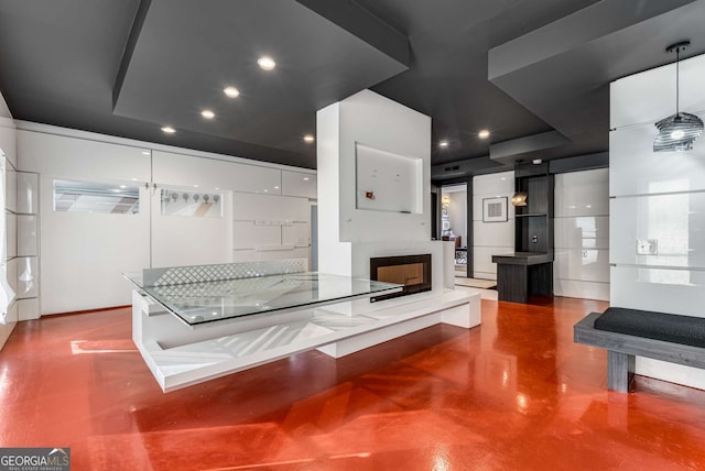 kitchen with hanging light fixtures, concrete flooring, and white cabinets