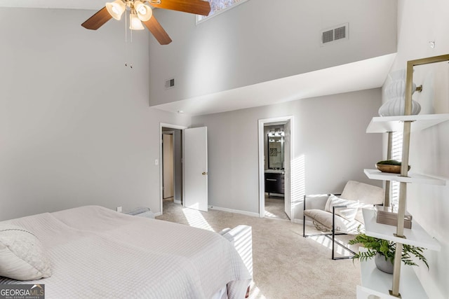 carpeted bedroom with ceiling fan, ensuite bathroom, and high vaulted ceiling