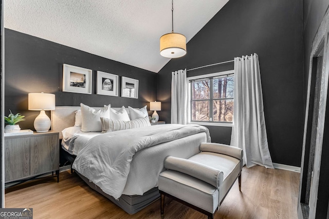 bedroom with lofted ceiling, wood-type flooring, and a textured ceiling