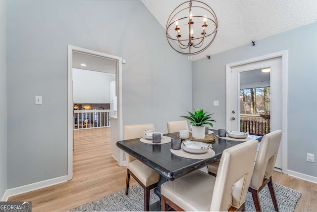 dining area with a notable chandelier, a textured ceiling, and light wood-type flooring