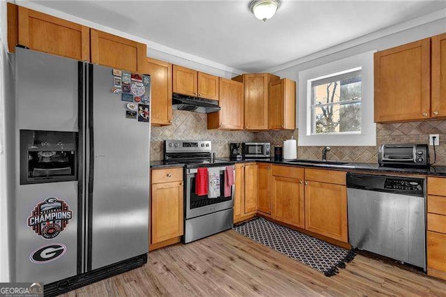 kitchen featuring crown molding, appliances with stainless steel finishes, tasteful backsplash, sink, and light wood-type flooring