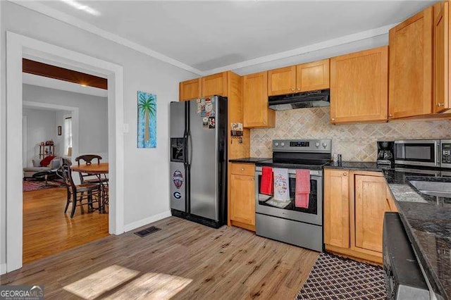 kitchen featuring appliances with stainless steel finishes, dark stone counters, backsplash, ornamental molding, and light wood-type flooring