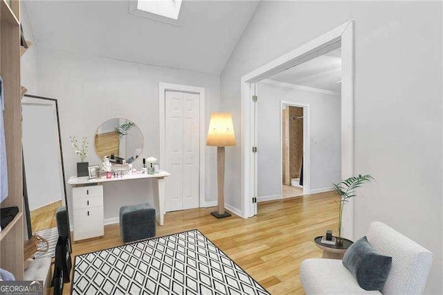 living area featuring light hardwood / wood-style floors, crown molding, and vaulted ceiling