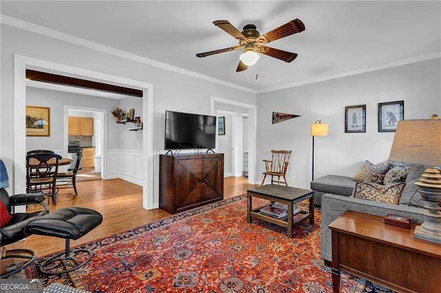 living room with ceiling fan, wood-type flooring, and ornamental molding