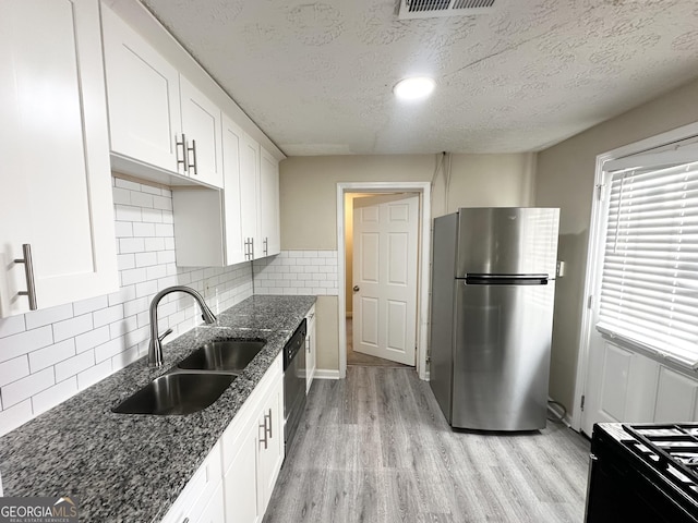 kitchen featuring white cabinets, stainless steel appliances, a textured ceiling, and backsplash