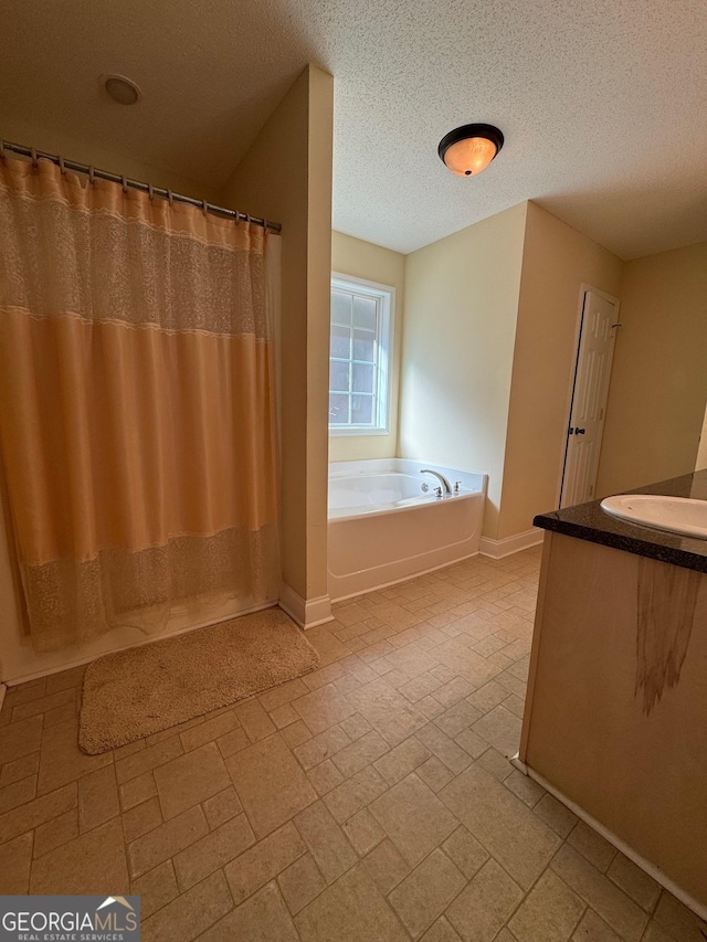 bathroom with a textured ceiling, a bath, and vanity