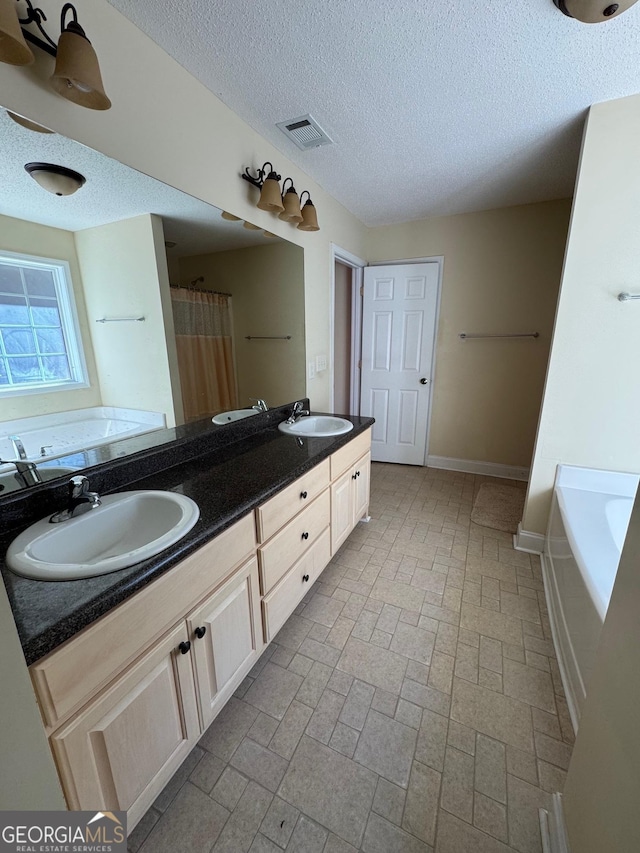 bathroom with a textured ceiling, shower with separate bathtub, and vanity