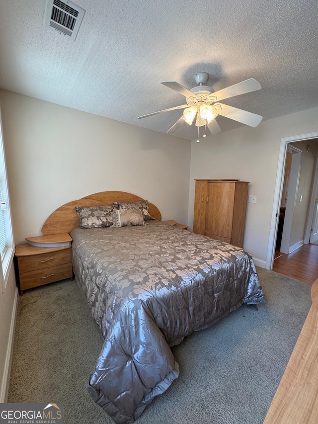 carpeted bedroom featuring ceiling fan and a textured ceiling