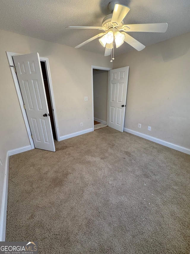 unfurnished bedroom featuring ceiling fan, carpet, and a textured ceiling