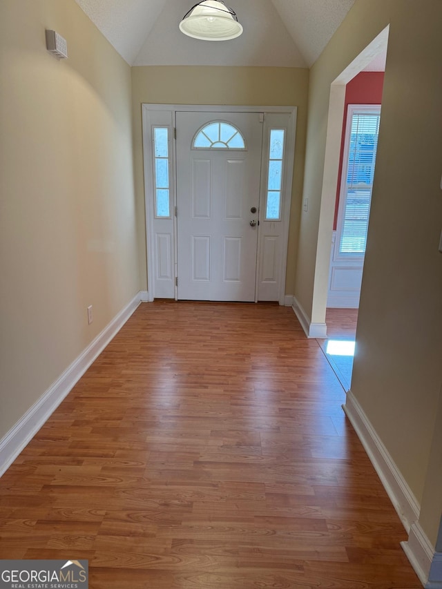 entryway featuring light hardwood / wood-style floors, a textured ceiling, and lofted ceiling