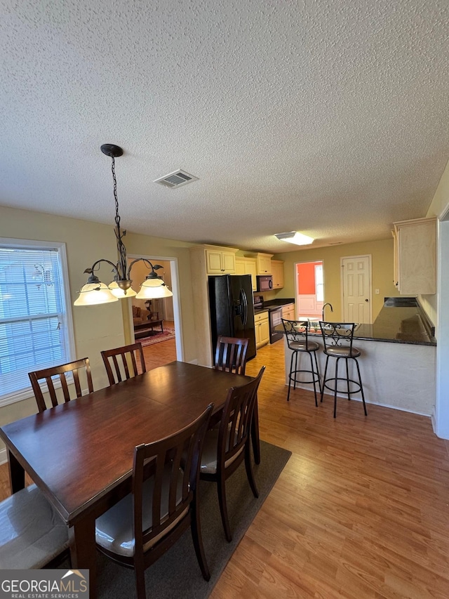 dining room with a textured ceiling, plenty of natural light, and light hardwood / wood-style flooring