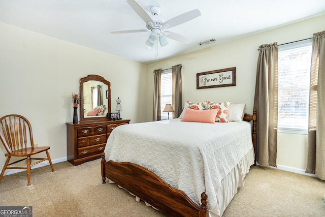 bedroom with ceiling fan, light colored carpet, and multiple windows