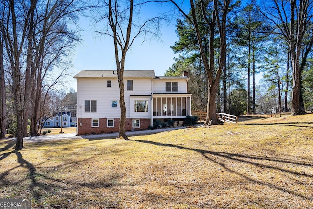 rear view of house with a sunroom and a lawn