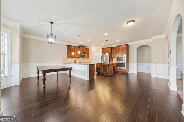 kitchen featuring pendant lighting, stainless steel appliances, backsplash, kitchen peninsula, and ornamental molding