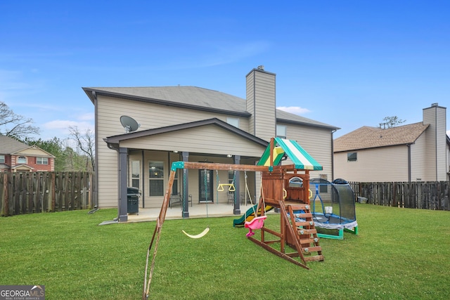 rear view of property with a playground, a yard, a trampoline, and a patio area