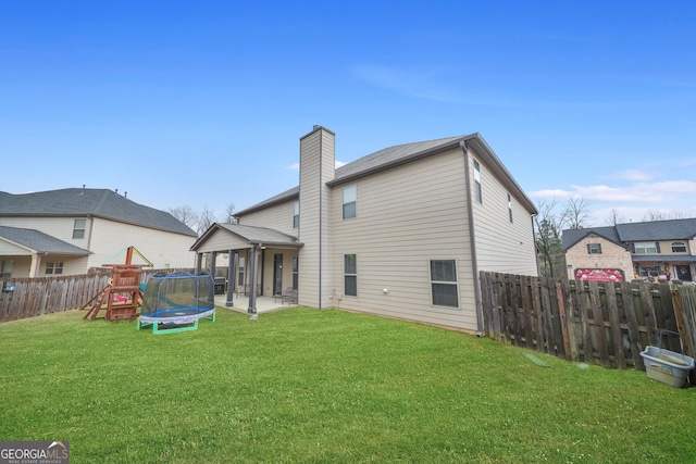 back of property with a playground, a patio area, a lawn, and a trampoline