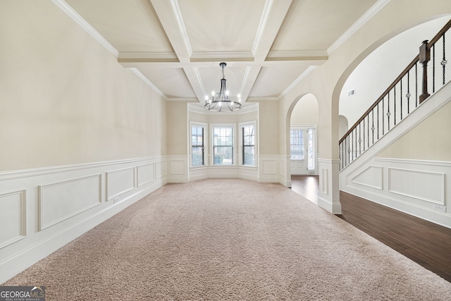 unfurnished living room featuring carpet floors, beamed ceiling, a notable chandelier, crown molding, and coffered ceiling