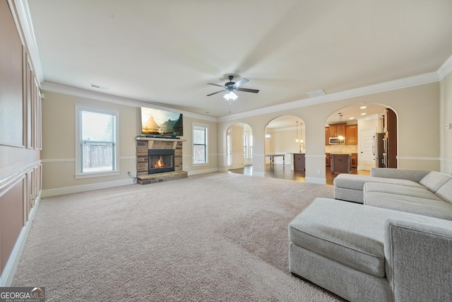 living room with a fireplace, ornamental molding, ceiling fan, and carpet flooring