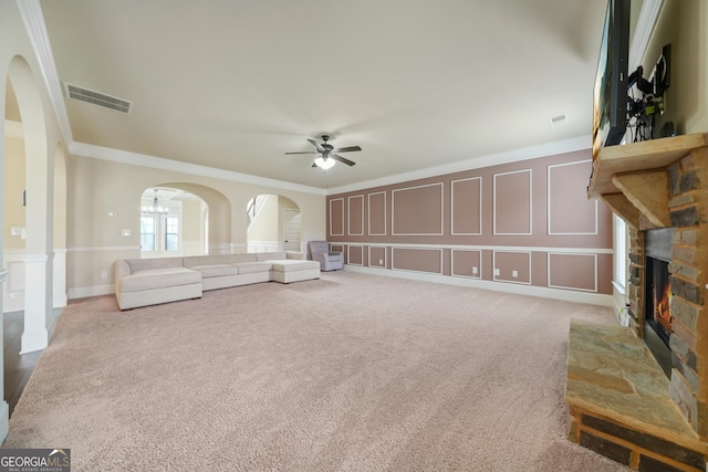 unfurnished living room featuring carpet floors, ceiling fan with notable chandelier, ornamental molding, and a fireplace