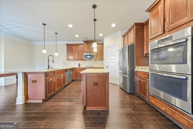 kitchen featuring light stone countertops, pendant lighting, stainless steel appliances, sink, and a center island with sink