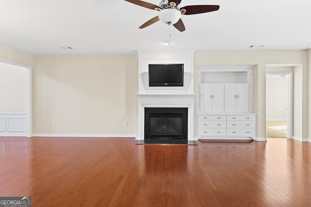 unfurnished living room featuring ceiling fan, wood-type flooring, and a fireplace