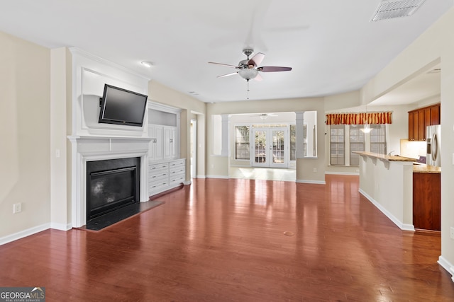 unfurnished living room featuring ceiling fan, dark wood-type flooring, and a fireplace