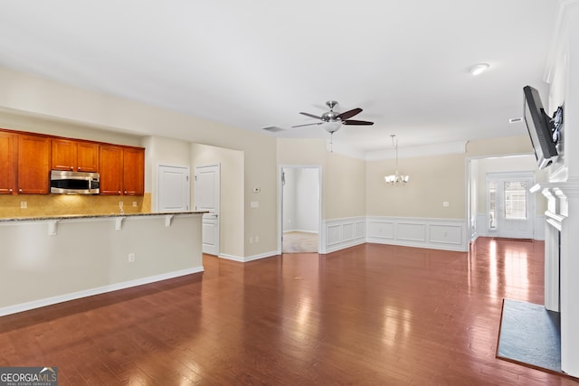 unfurnished living room featuring ceiling fan with notable chandelier and dark hardwood / wood-style flooring