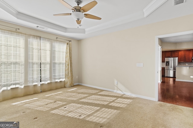 carpeted spare room featuring ceiling fan, a raised ceiling, and crown molding