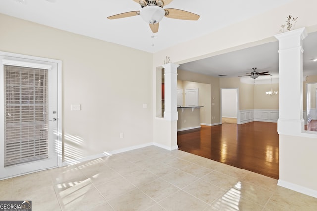 empty room with ceiling fan with notable chandelier, light tile patterned floors, and ornate columns