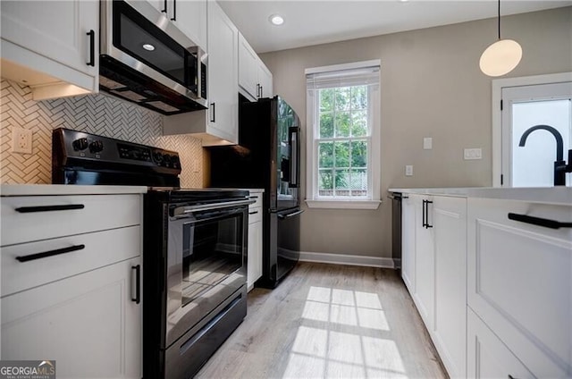 kitchen featuring light wood-type flooring, tasteful backsplash, white cabinetry, stainless steel appliances, and light countertops