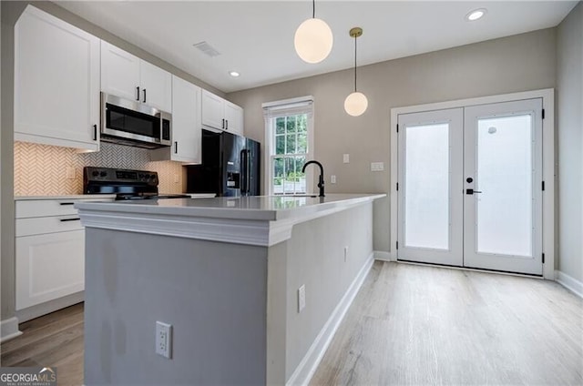 kitchen with black appliances, french doors, white cabinets, light wood finished floors, and decorative backsplash