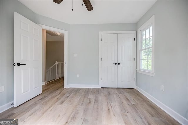 unfurnished bedroom with a closet, ceiling fan, baseboards, and wood finished floors