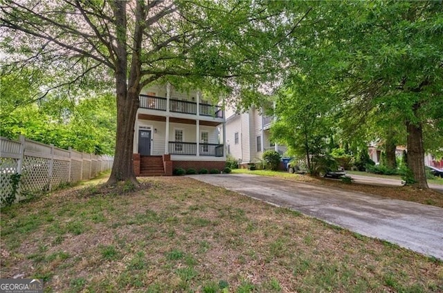 view of front of property featuring concrete driveway, a balcony, fence, and covered porch