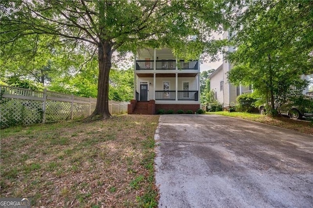 view of front of house featuring a porch, a balcony, and fence