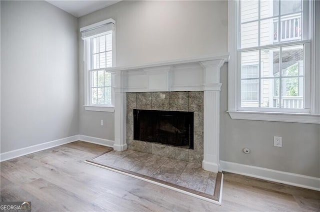 interior details featuring baseboards, wood finished floors, and a tiled fireplace