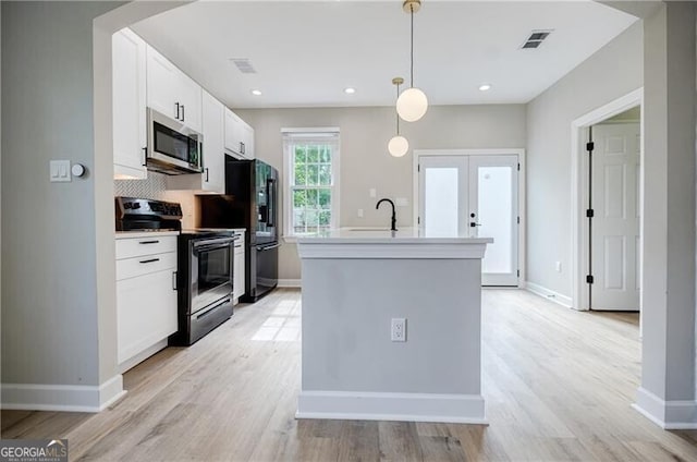 kitchen with arched walkways, visible vents, appliances with stainless steel finishes, and an island with sink