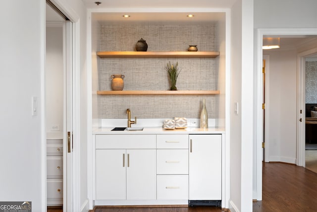 bar featuring dark wood-type flooring, a sink, and refrigerator