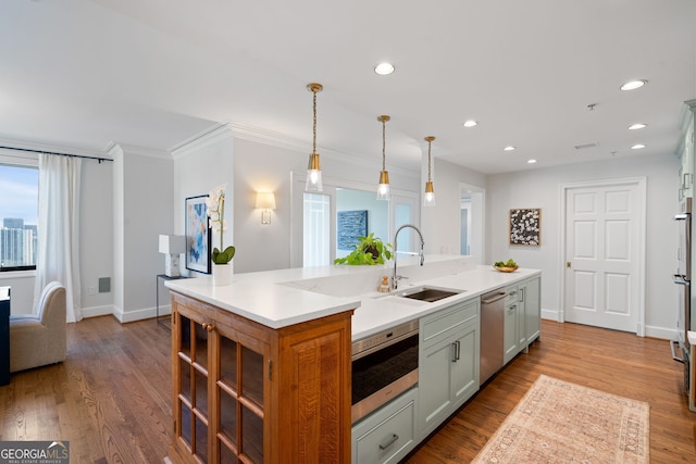 kitchen with a sink, light countertops, hanging light fixtures, stainless steel dishwasher, and a center island with sink