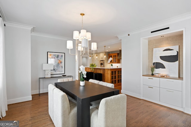 dining space with light wood-style floors, ornamental molding, baseboards, and an inviting chandelier