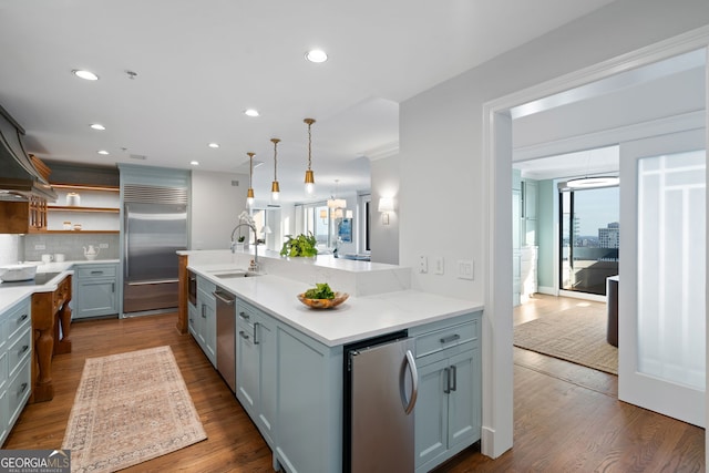 kitchen with dark wood-style floors, appliances with stainless steel finishes, a sink, and pendant lighting