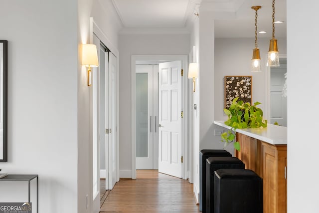 corridor with ornamental molding and wood finished floors