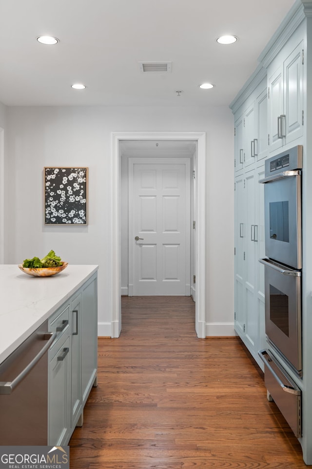 kitchen featuring a warming drawer, stainless steel appliances, dark wood-style flooring, and recessed lighting