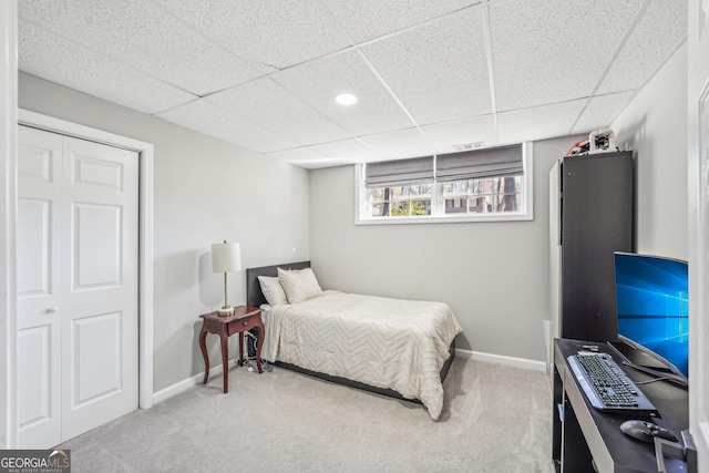 carpeted bedroom with a paneled ceiling and a closet